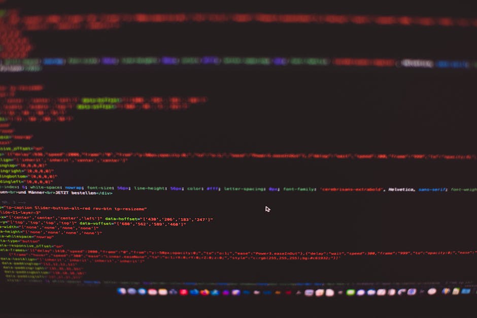 Close-up view of a MacBook Pro displaying a webpage editing code with HTML tags such as <section>, <div>, <h1>, and <p>. The screen shows a text editor with color-coded syntax highlighting for differe