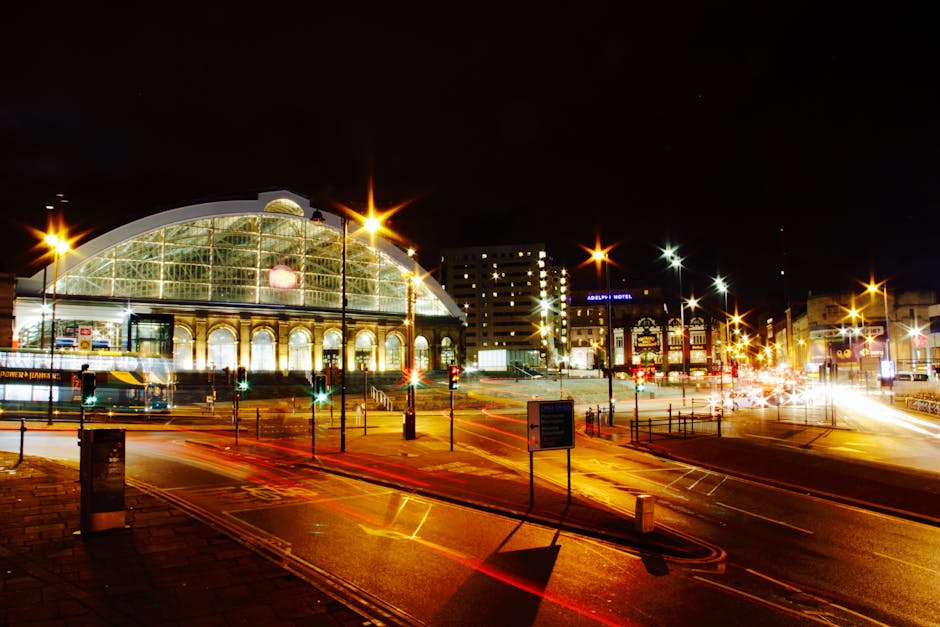 A scene at Liverpool Street Station featuring a small shop entrance with snacks and confectionery items displayed outside, illuminated with vibrant purple lighting. To the right, there is a waiting ar
